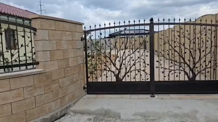 Ażurowa brama kuta z drzewami i ogrodzenie z liśćmi